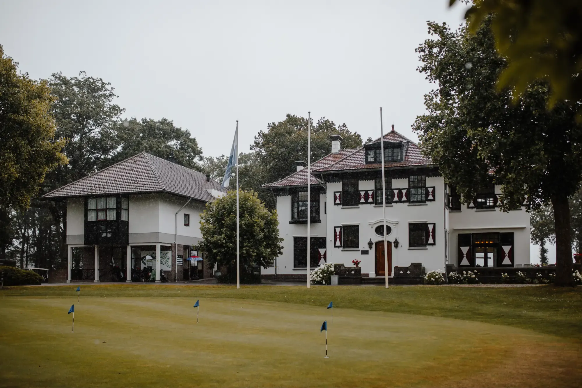 Het witte clubhuis van de Noord Nederlandse Golf & Country Club met de golfbaan ervoor
