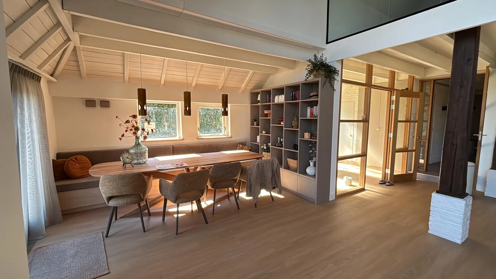 De eethoek met een bank op maat, een houten tafel en een grote vakkenkast
