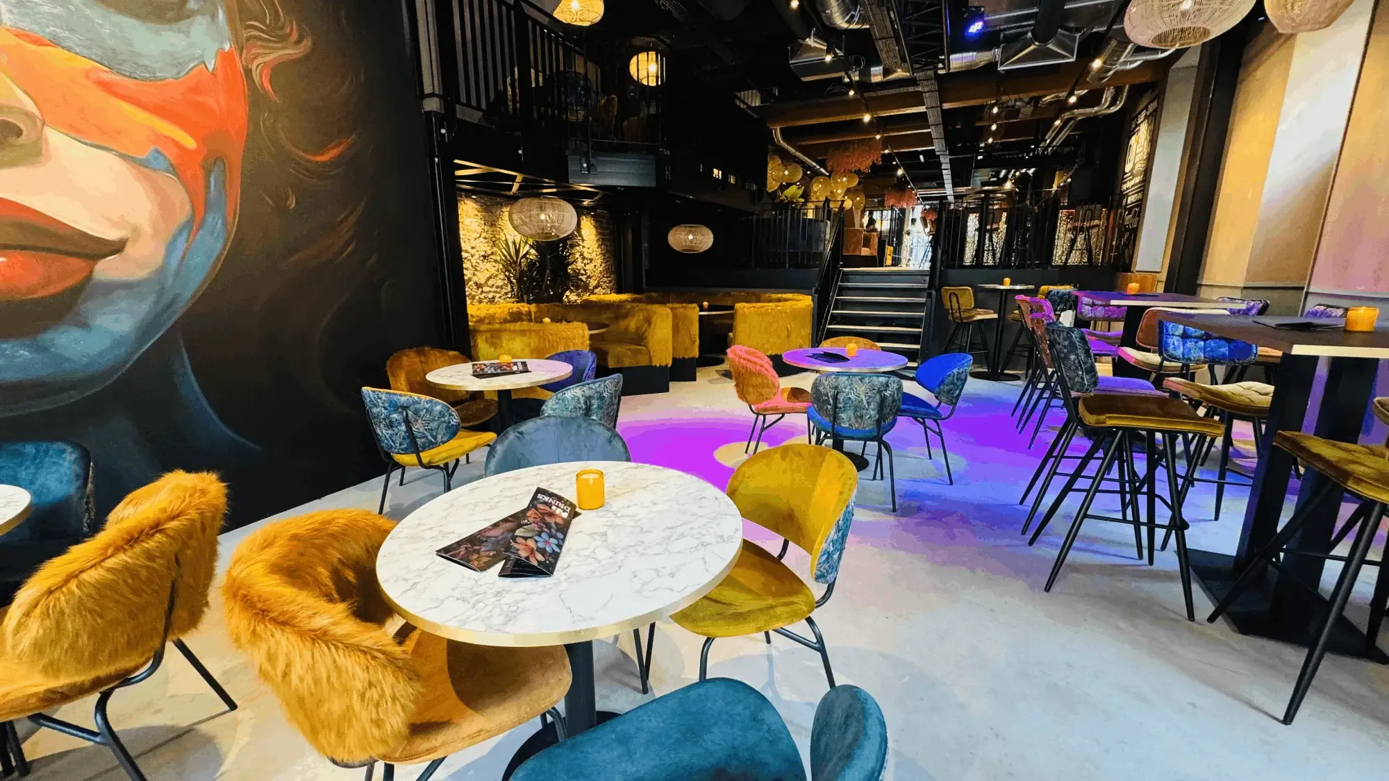 Het restaurant van PJ's in Groningen, met een grote muurschildering en gekleurde stoelen