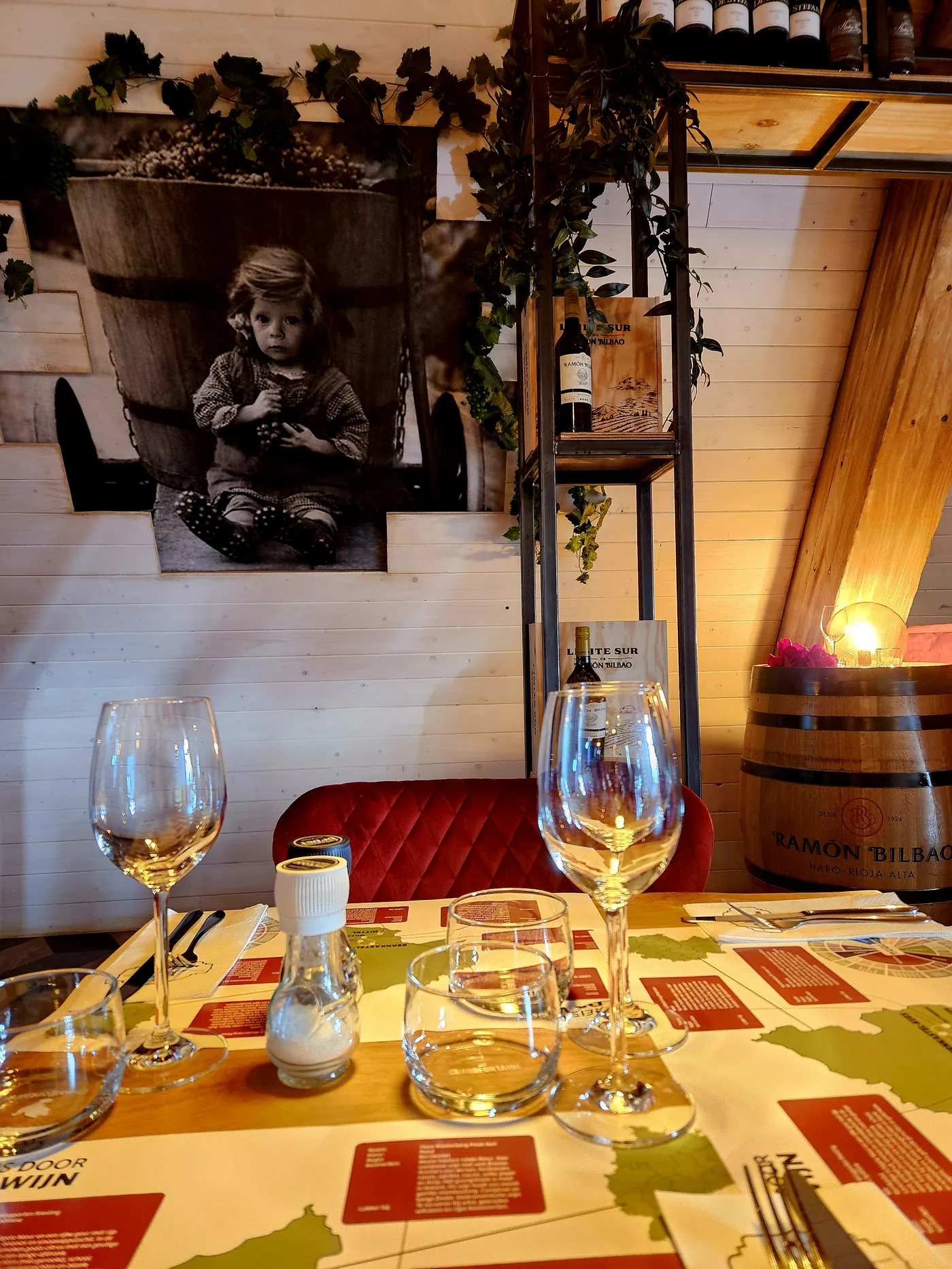 Een zwart-witfoto op de wand, met wijnglazen op de gedekte tafel ervoor