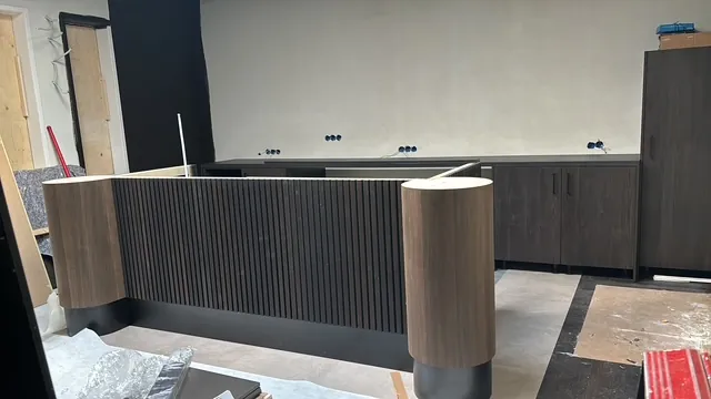 De bar van Sondrio tijdens de bouw: een donker front met verticale latten tussen twee ronde houten koppen